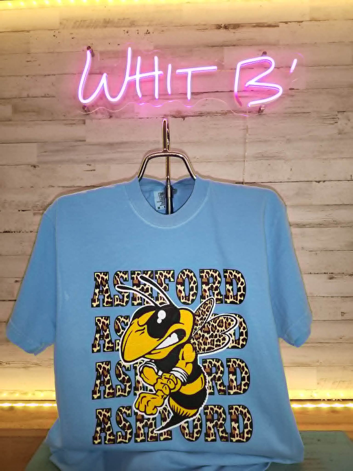 Light blue Ashford shirt with leopard-print lettering and Yellow Jacket mascot
