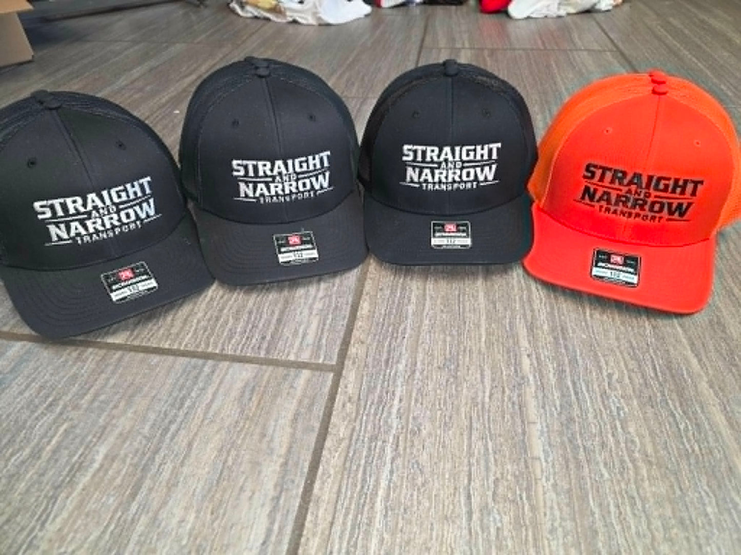 Black and orange caps embroidered with the Straight & Narrow Transport logo
