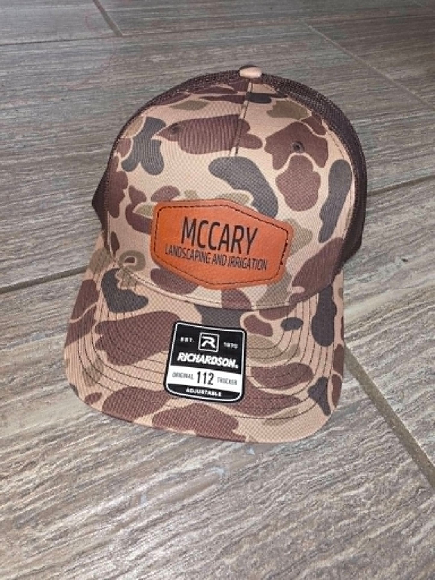 Brown camouflage trucker hat with McCary Landscaping and Construction leather patch