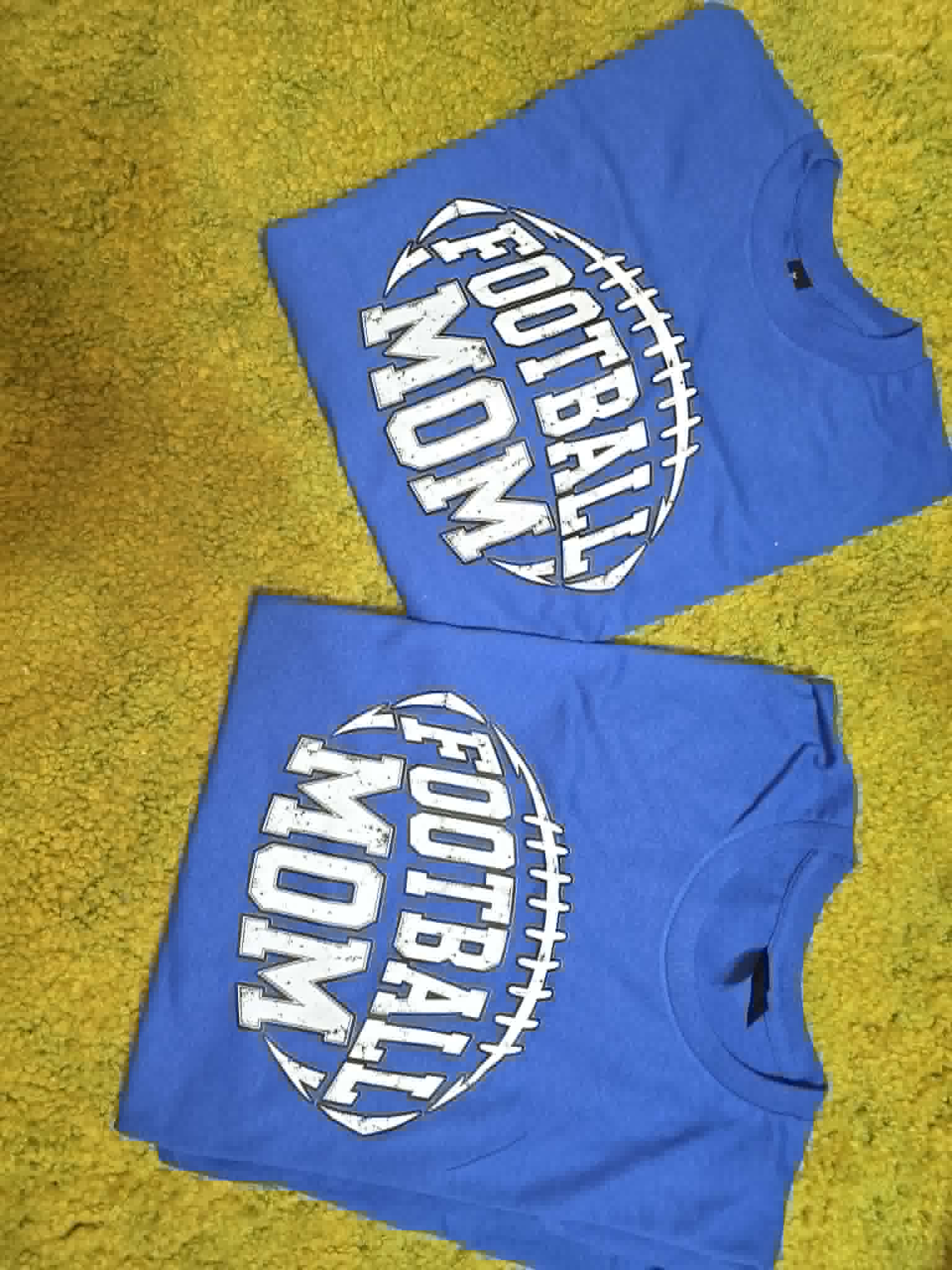 Blue Football Mom shirts with distressed white lettering inside a football