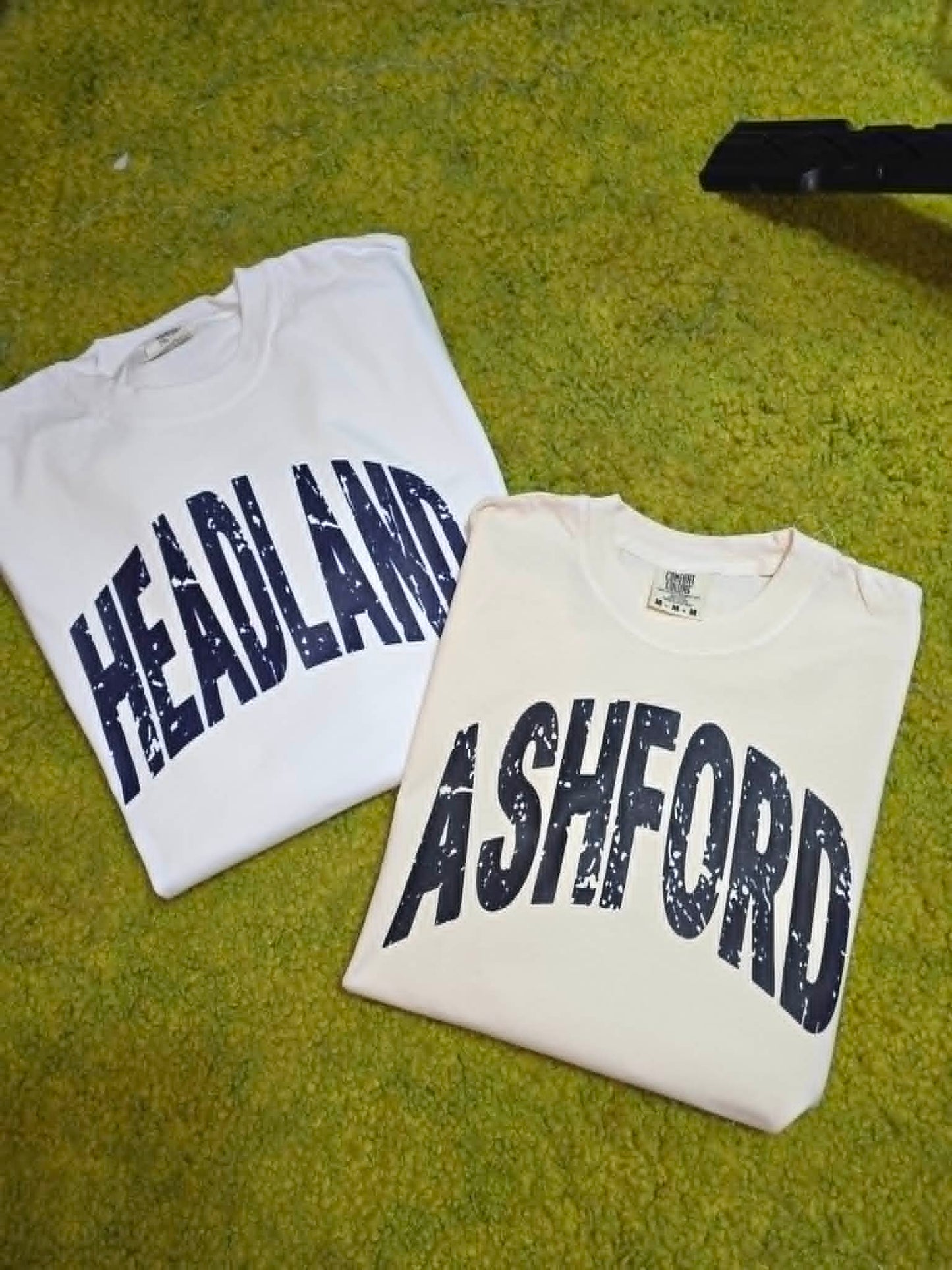 White Heflin and Ashford school spirit shirts with distressed navy lettering