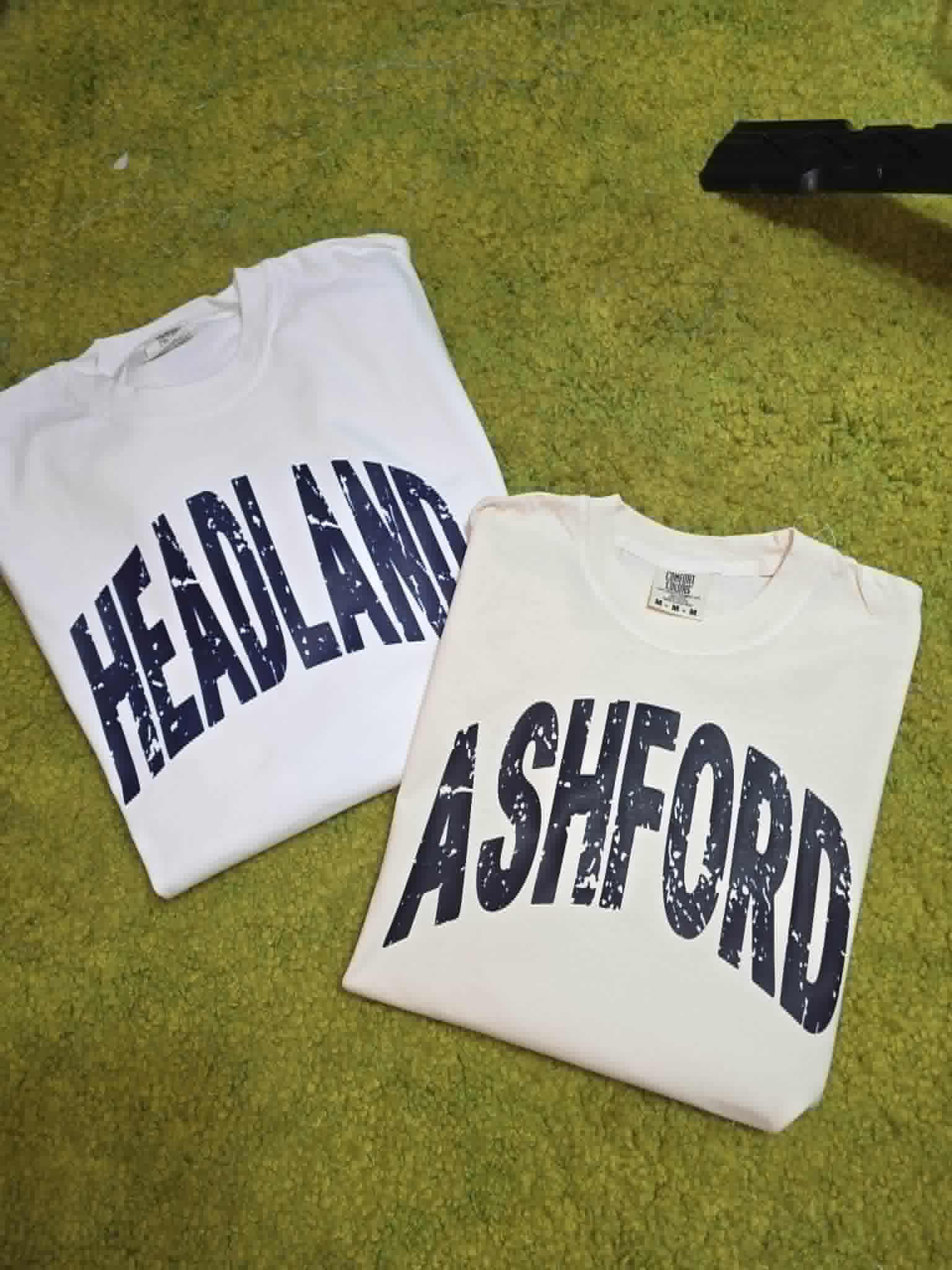 White Heflin and Ashford school spirit shirts with distressed navy lettering