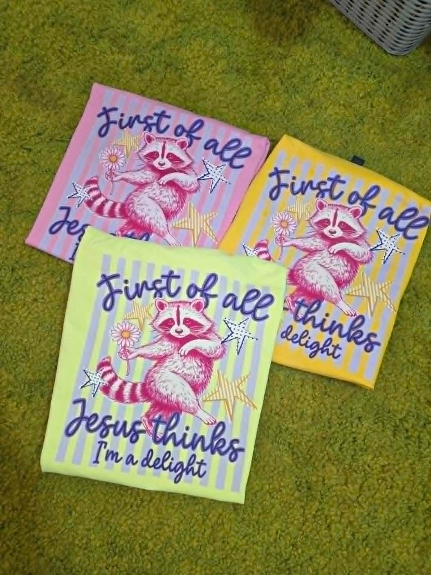 Colorful shirts with raccoon, stars, flowers, and First of All Jesus Thinks I'm a Delight wording