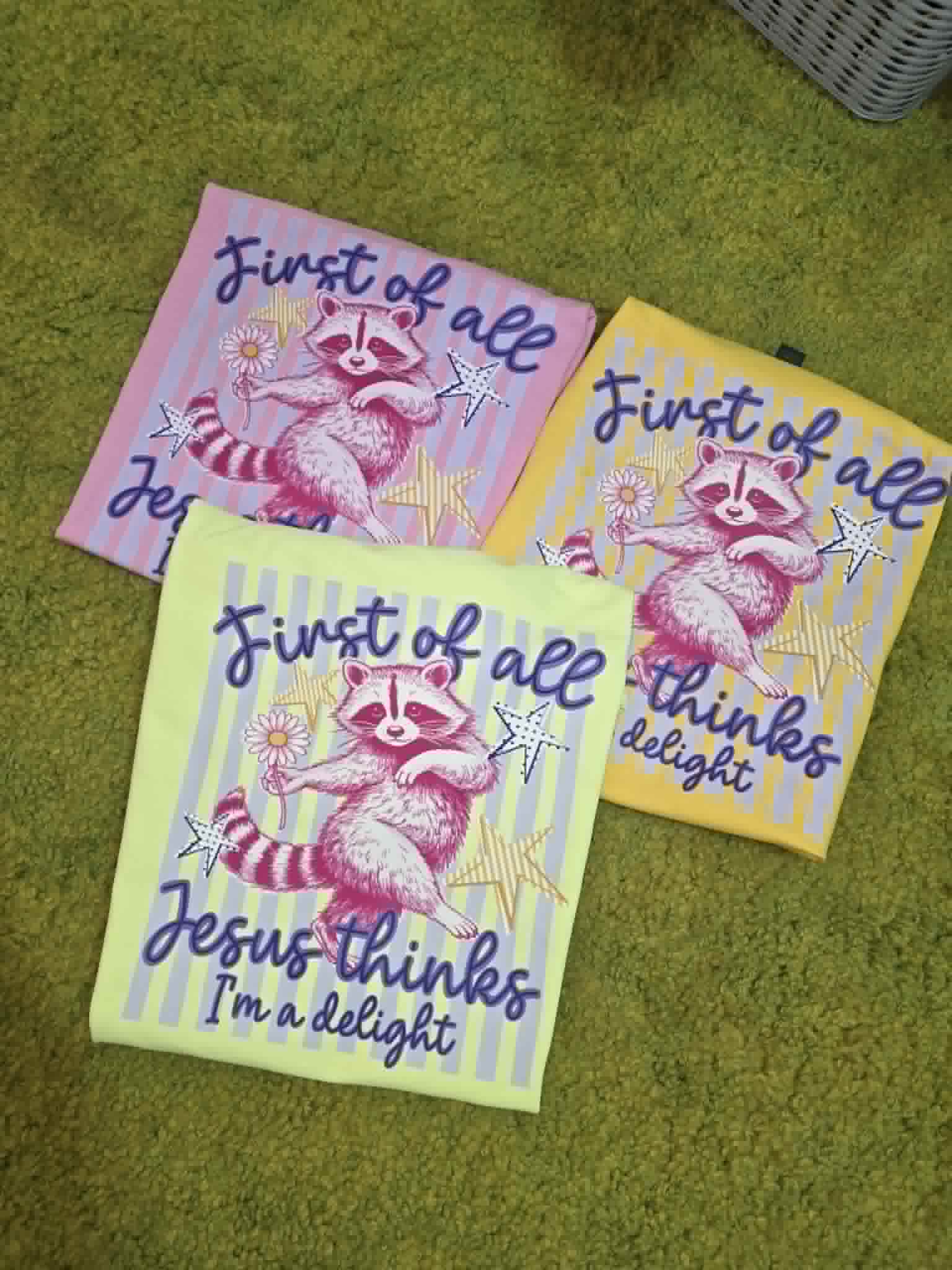 Colorful shirts with raccoon, stars, flowers, and First of All Jesus Thinks I'm a Delight wording