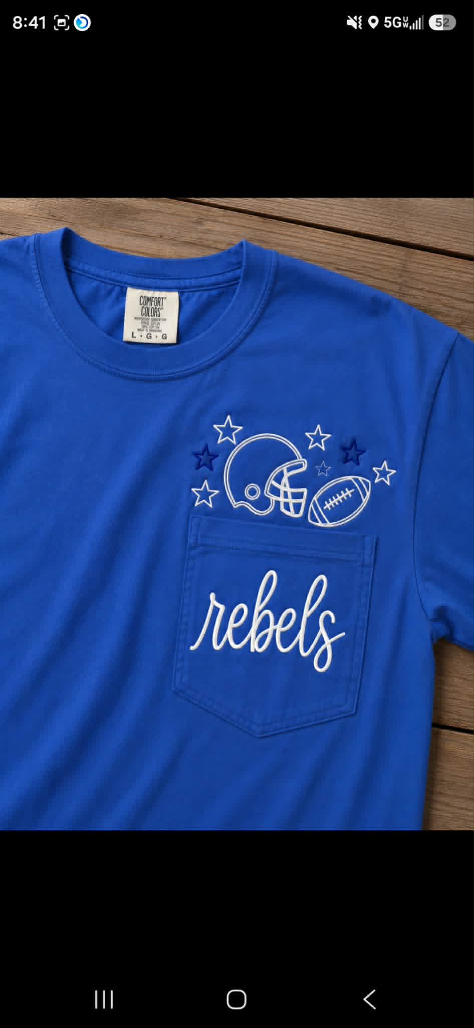 Blue pocket tee embroidered with football helmet, stars, ball, and Rebels script