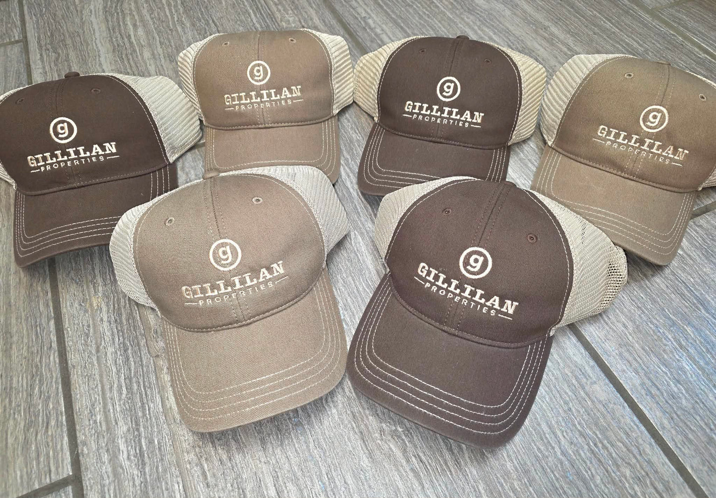 Brown and tan mesh trucker hats embroidered with the Gillilan Properties logo