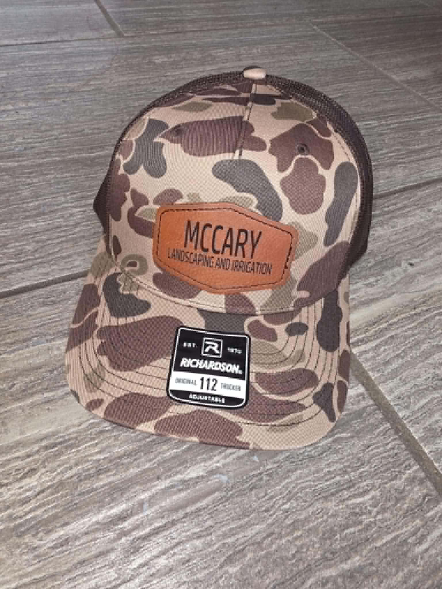 Brown camouflage trucker hat with McCary Landscaping and Construction leather patch