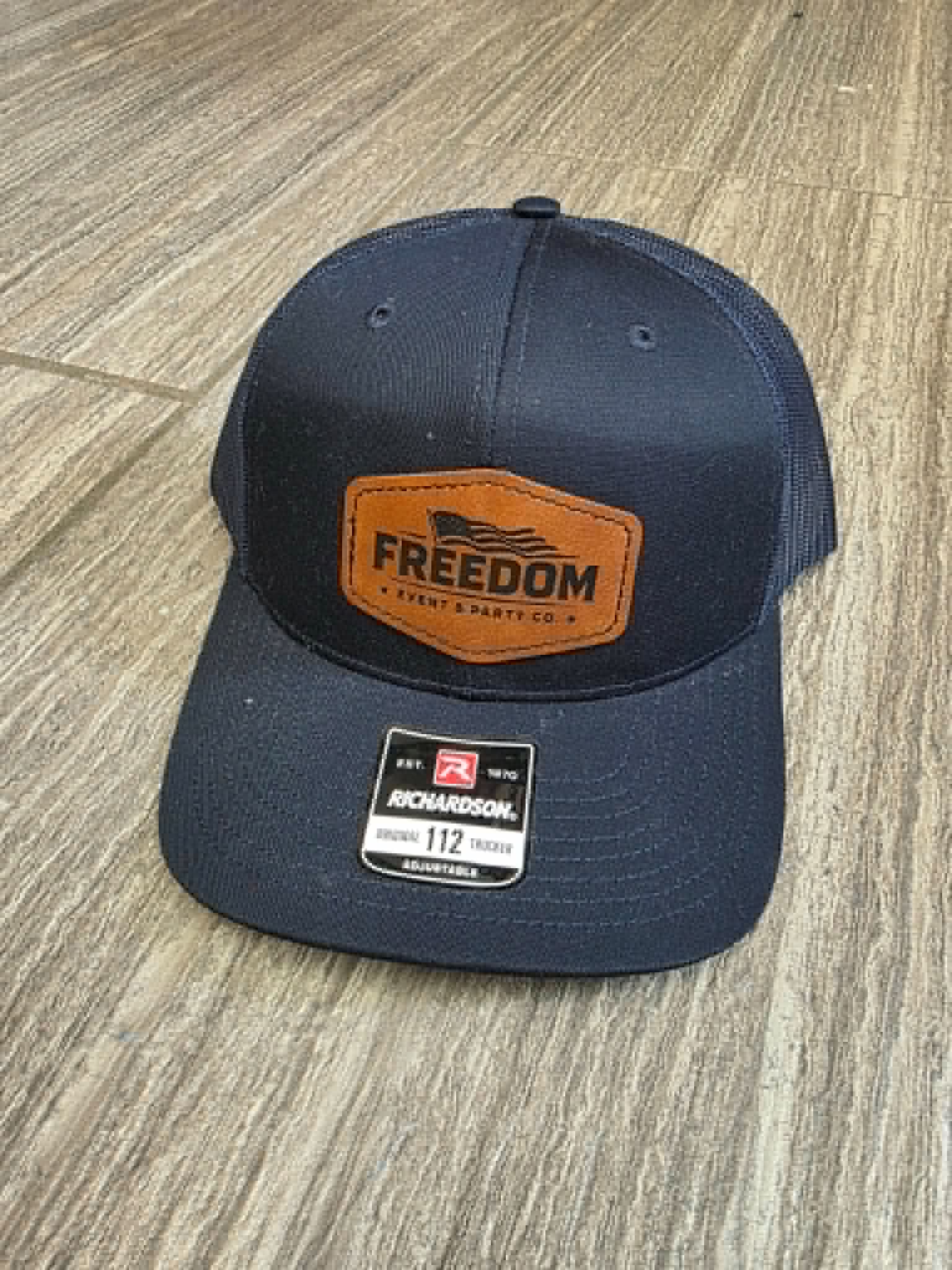 Navy trucker hat with a Freedom Event and Party Co. engraved leather patch