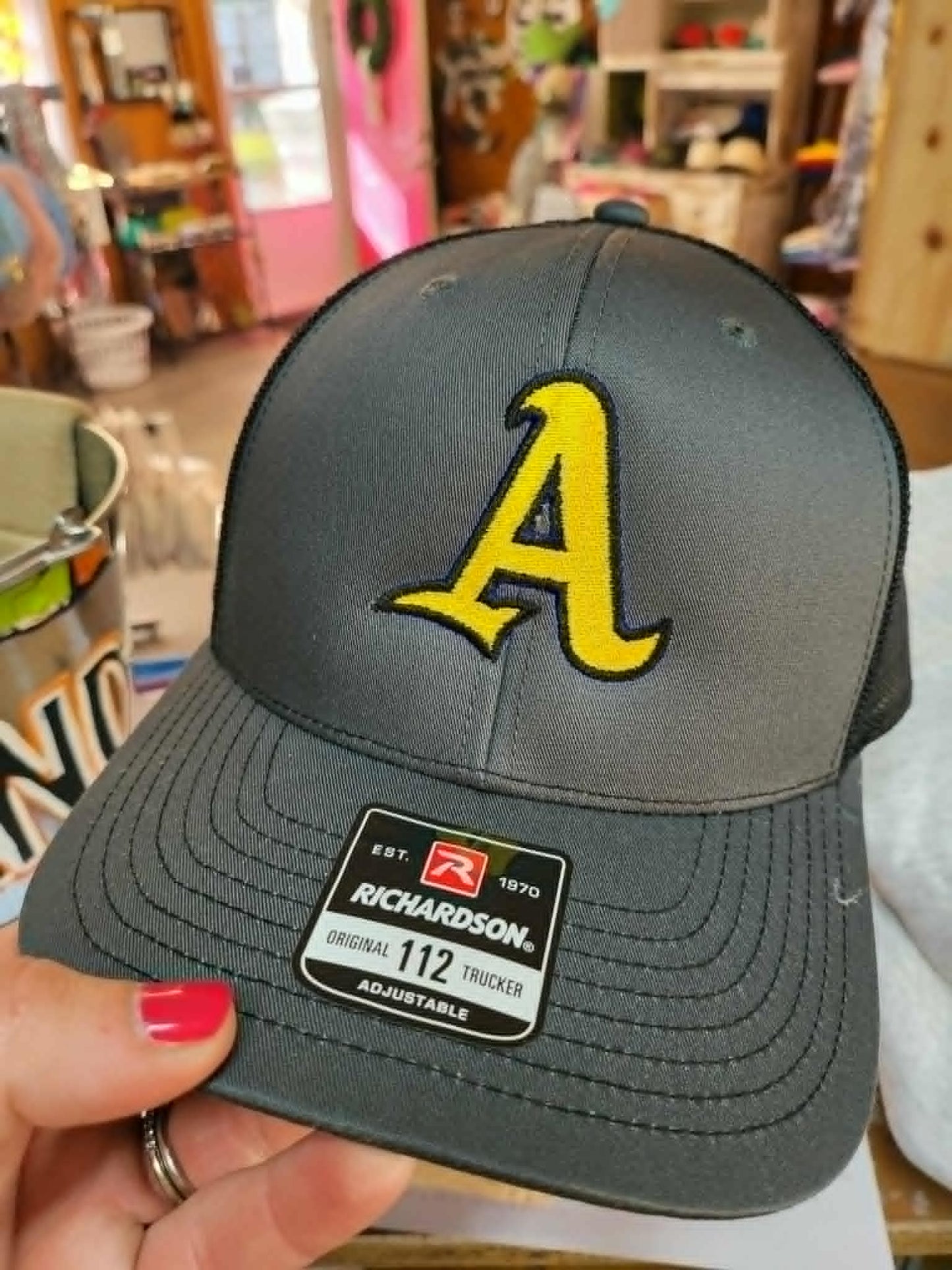 Gray and black Richardson trucker hat embroidered with a gold Ashford varsity A